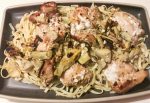 Gray serving platter containing fresh pasta, artichokes, broiled chicken thighs, and feta cheese