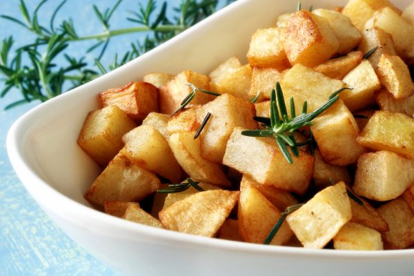 crispy roasted potatoes in a white bowl with rosemary