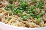 Sesame Chicken Lo Mein topped with green scallions and sesame seeds