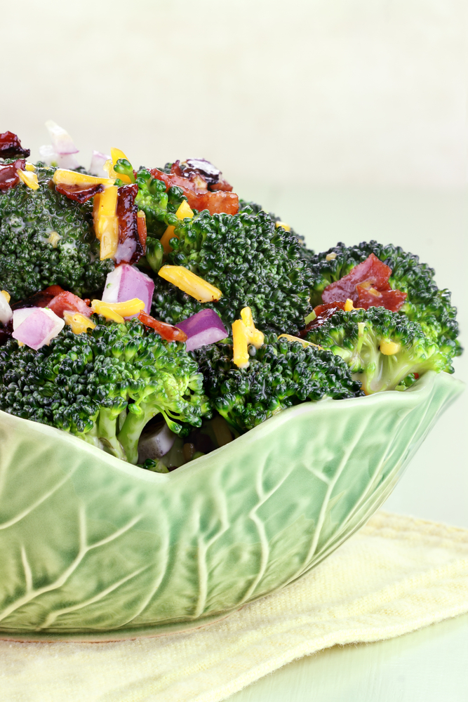 Green bowl filled with broccoli and bacon salad