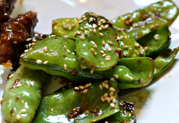 Sesame Snap Peas on white plate with rice and beef in background