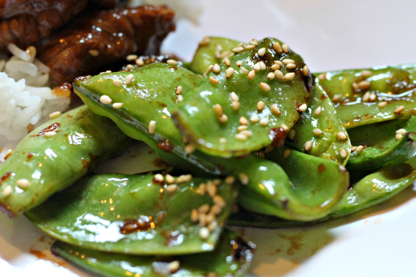 Sesame Snap Peas on white plate with rice and beef in background