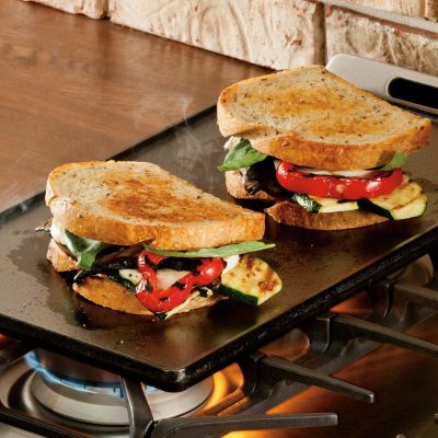 Sandwiches cooking on a plancha grill on gas oven top