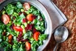 Salad in a white bowl with additional white bowl containing Disney's Ohana honey lime dressing