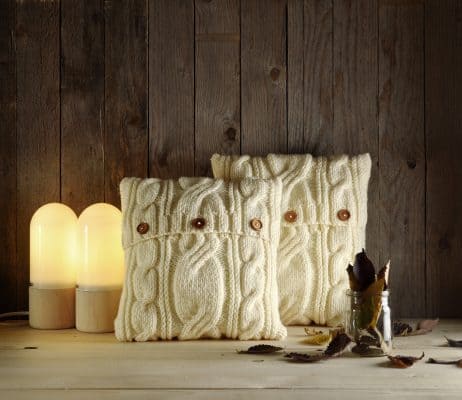 White sweater knit pillows against wooden backdrop