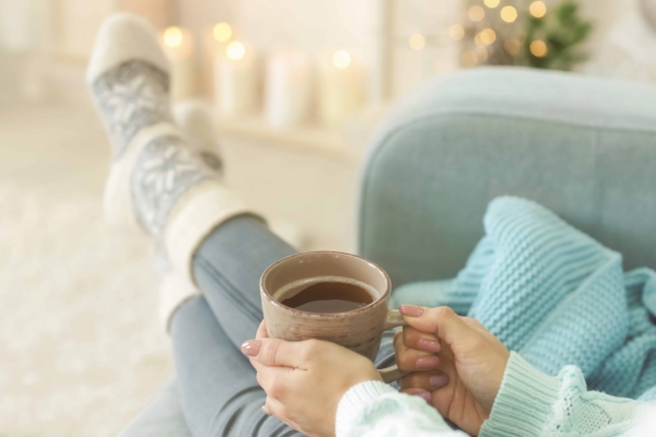 non descript woman holding a cup of coffee while relaxing via candlelight