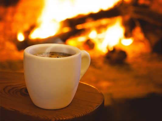 mug of steaming coffee by fireplace