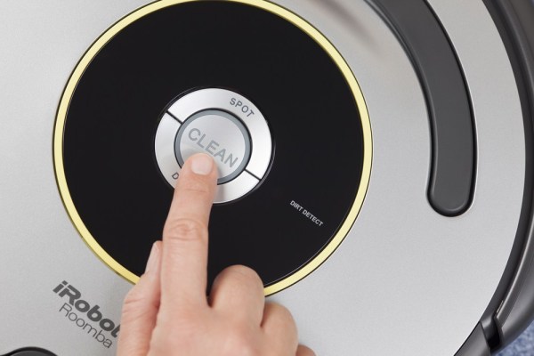 Finger pushing the clean button on a roomba