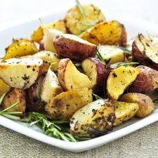 White plate with 3 ingredient roasted potatoes garnished with rosemary sprigs