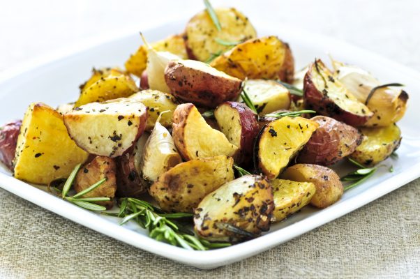 White plate with 3 ingredient onion roasted potatoes garnished with rosemary sprigs