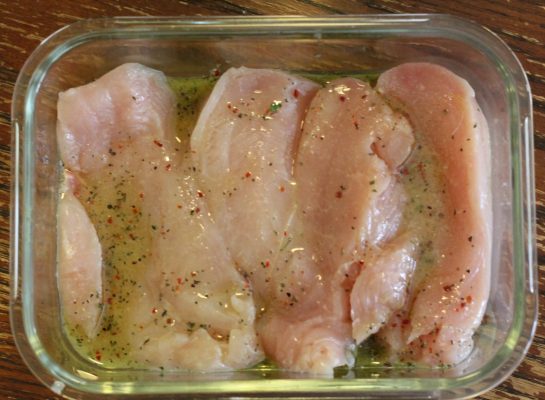 chicken breasts marinating in a glass container