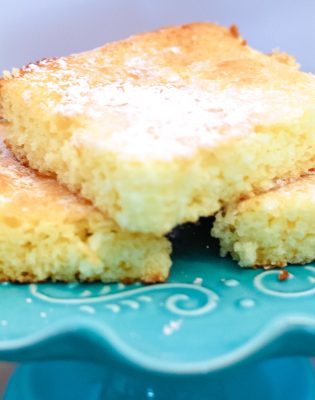 3 lemon cake bars stacked on a turquoise cake stand