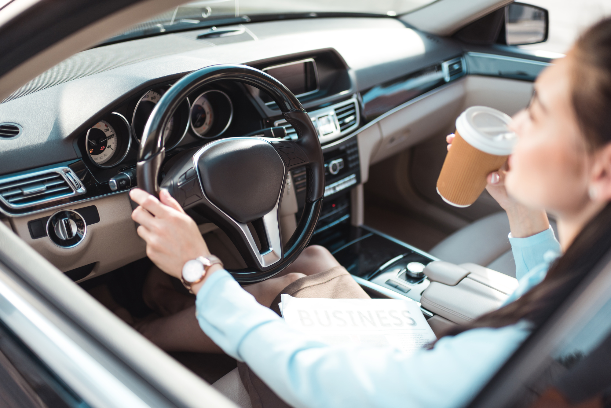 woman driving in car, drinking coffee from travel cup