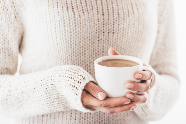 Warming cup of coffee in the hands of women