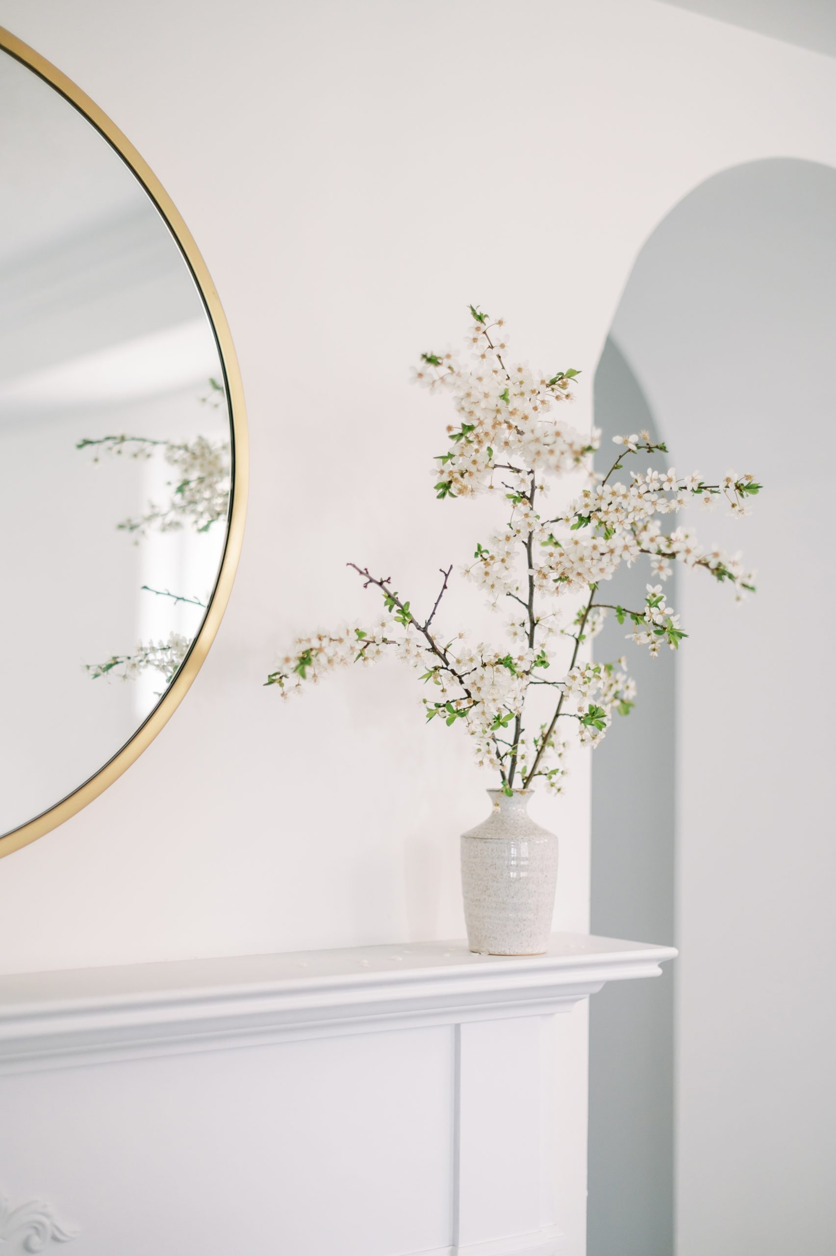 face of flowers on a shelf next to a round mirror