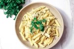 Pesto Chicken Pasta bowl on a a white wooden table