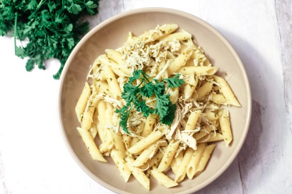 Pesto Chicken Pasta bowl on a a white wooden table