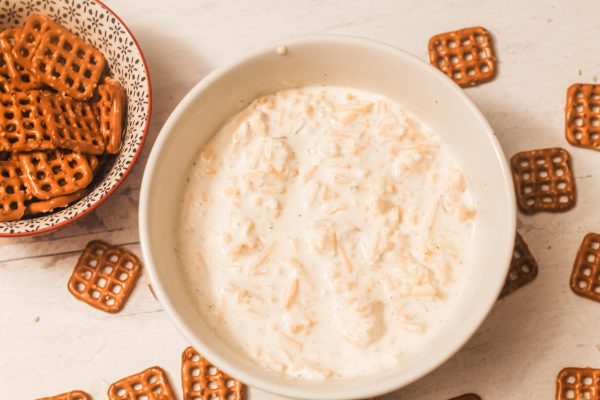 white bowl of beer cheese dip and bowl of square pretzels
