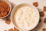 white bowl of beer cheese dip and bowl of square pretzels