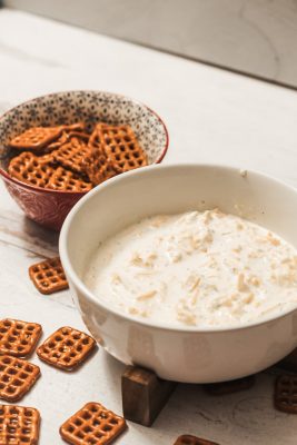 white bowl of beer cheese dip and bowl of square pretzels