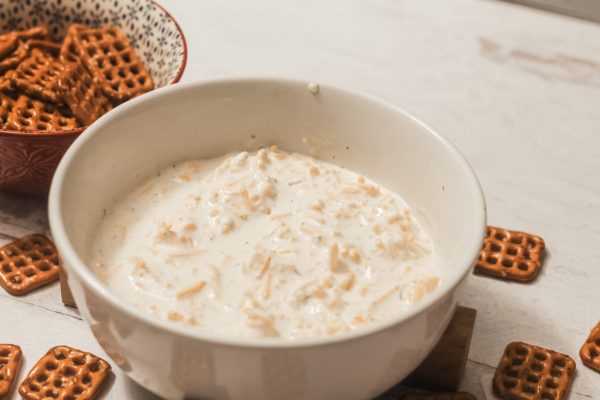 white bowl of beer cheese dip and bowl of square pretzels