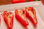 Red Mini-Peppers stuffed with baked goat cheese on a white tray
