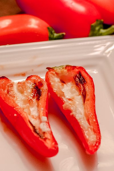 Red Mini-Peppers stuffed with baked goat cheese on a white tray