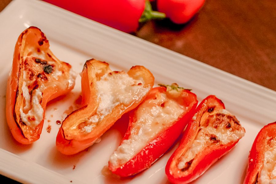Red Mini-Peppers stuffed with baked goat cheese on a white tray