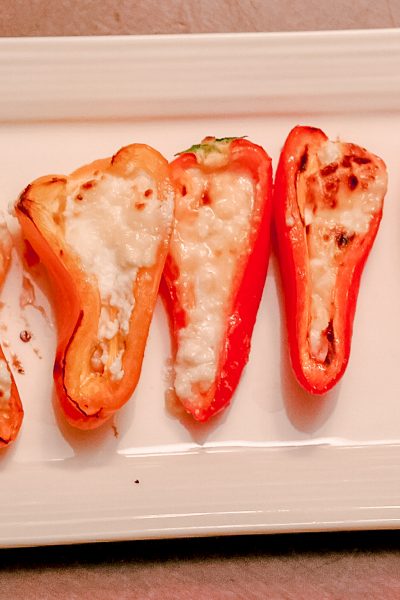 Red Mini-Peppers stuffed with baked goat cheese on a white tray