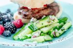 hamburger, mixed berries, and matchstick cucumber salad on a teal plate