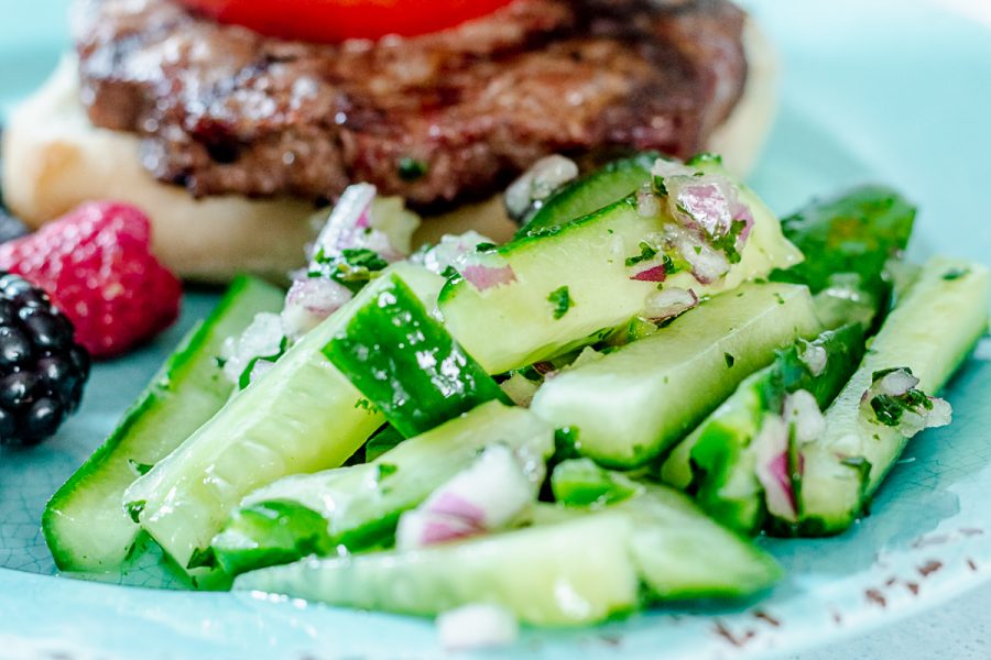 close up on spicy cucumber salad on a teal plate