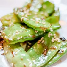 Sesame Snap Peas on white plate with rice and beef in background