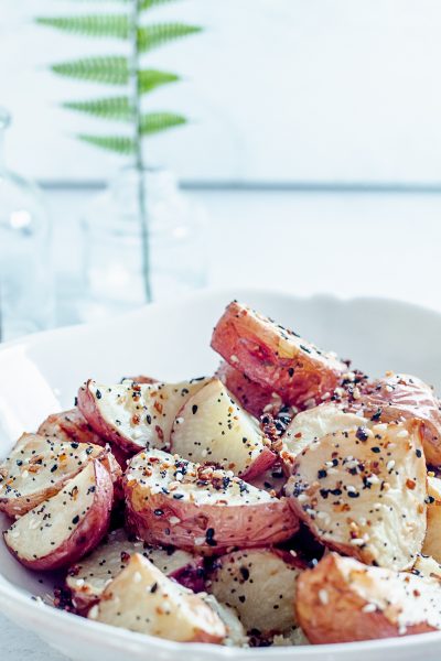 white bowl containing roasted potatoes topped with everything bagel seasoning