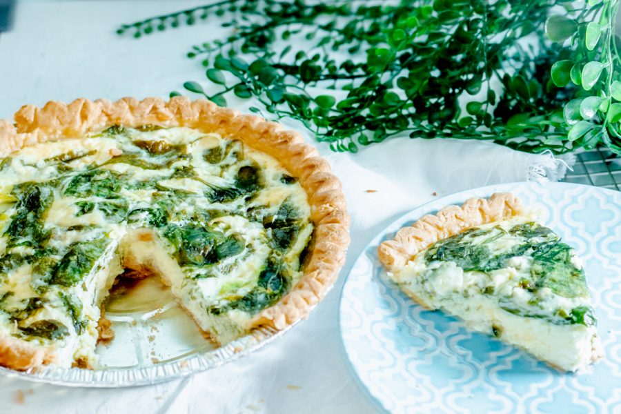 spinach quiche with a piece missing and blue plate containing slice of quiche
