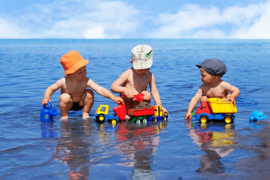 3 boys playing with trucks in a lake