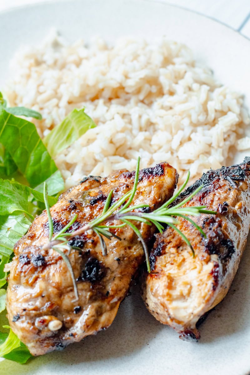 rosemary grilled chicken on a plate with rice and salad