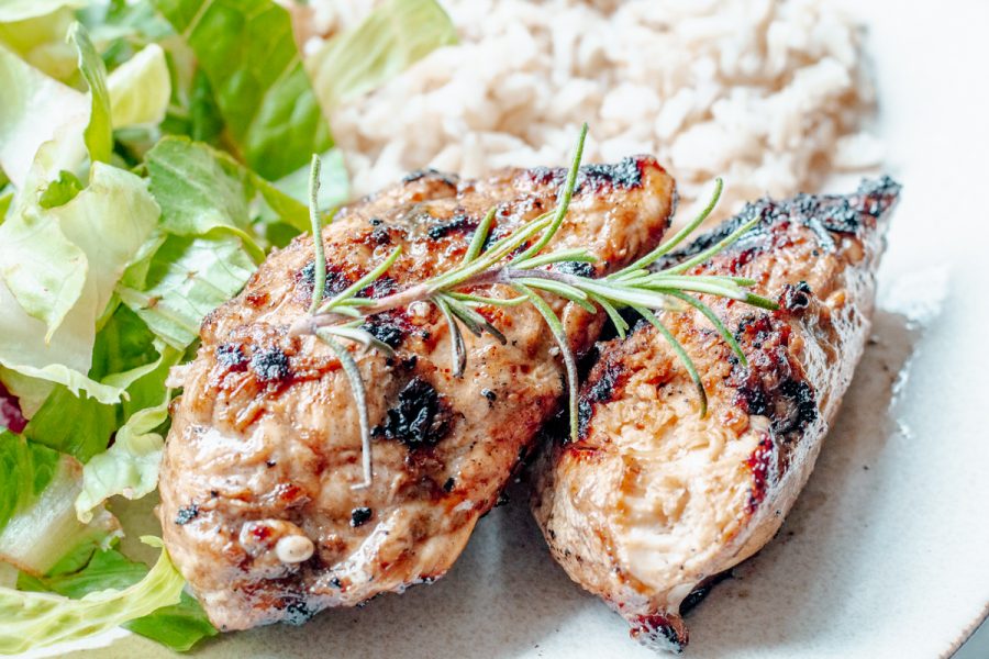 rosemary grilled chicken on a plate with rice and salad