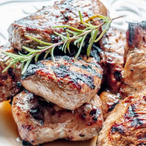 close up of plate of grilled chicken topped with a swig of rosemary
