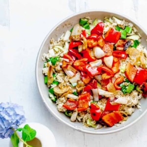 Bowl of roasted veggies and za'atar rice and a white vase with a blue hydrangea