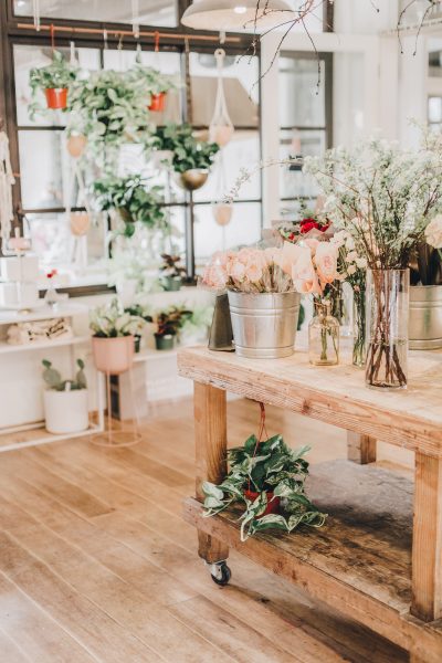 room filled with hanging baskets of plants and bins and vases of fresh cut flowers