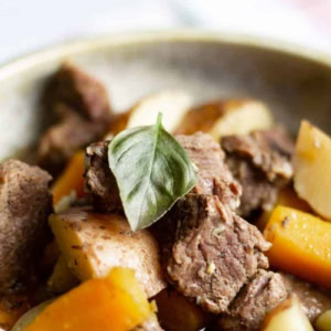 close up of easy instant pot beef stew with a basil leaf on top