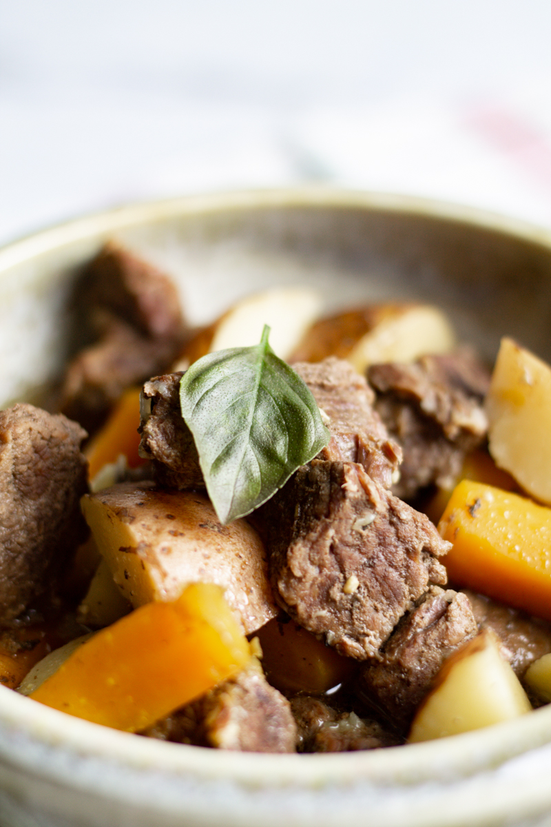 close up of easy instant pot beef stew with a basil leaf on top