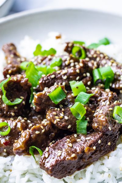 close up of mongolian beef over rice with green onions