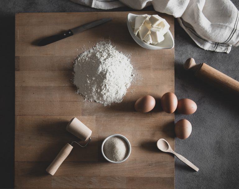 wooden cutting board with eggs, flour, and butter