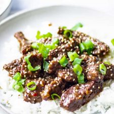 close up of mongolian beef over rice with green onions