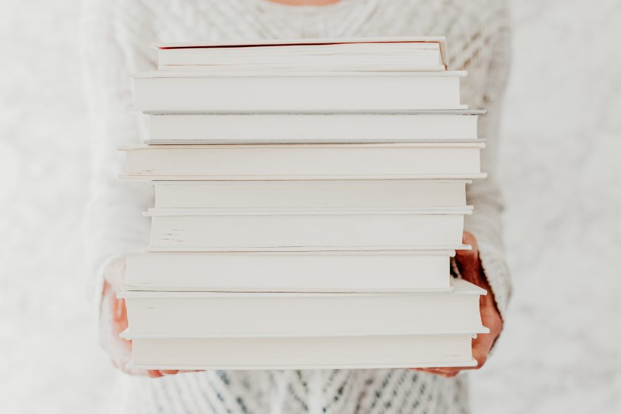 woman carrying stack of books about hygge