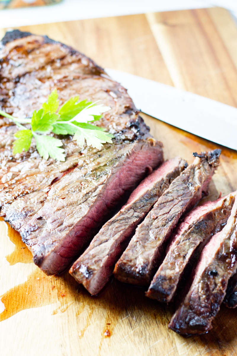 sliced marinated london broil on a wooden cutting board