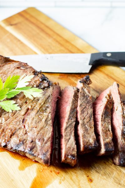 sliced marinated london broil on a wooden cutting board