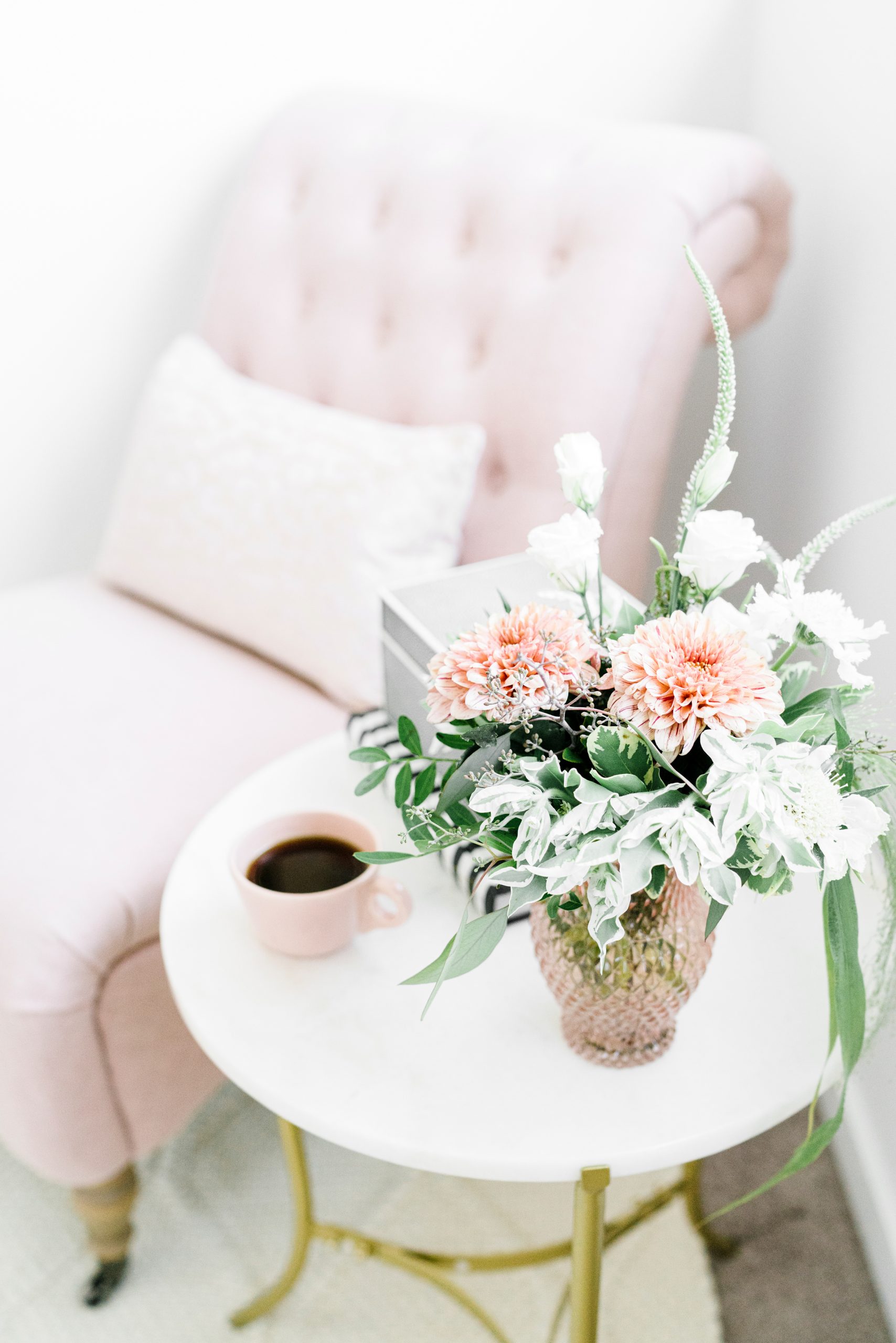 end table with flowers and coffee cup next to a cozy chair