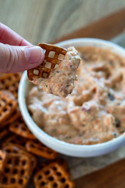 square pretzel dipped into roasted red pepper vegetable dip